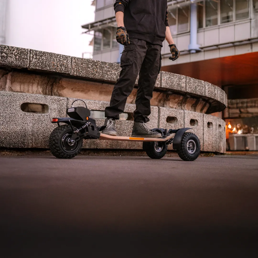 Rider Sternboard en entorno urbano contemporáneo de noche con skateboard eléctrico de tres ruedas
