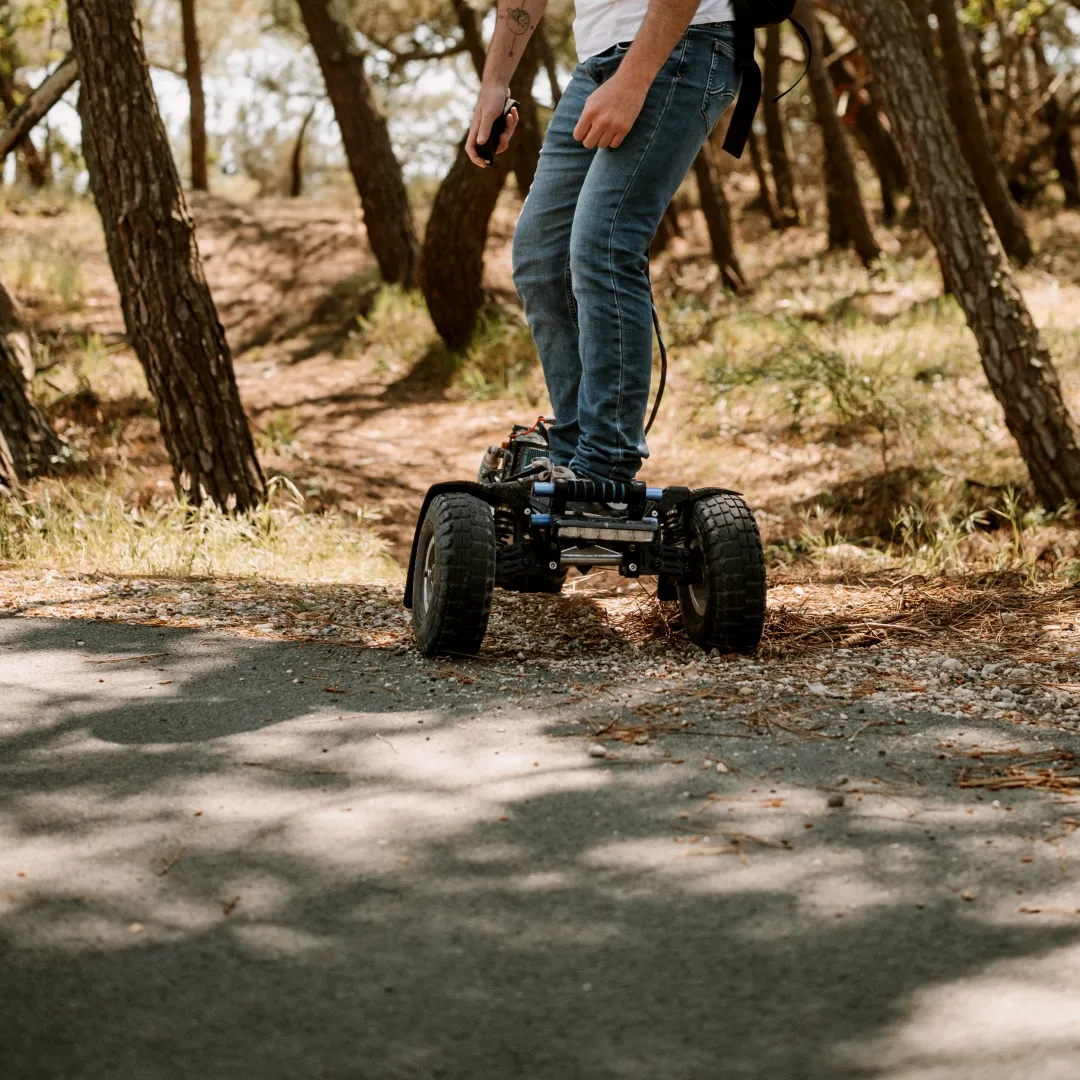 Rider Sternboard recorriendo un camino forestal con skateboard eléctrico de tres ruedas todo terreno