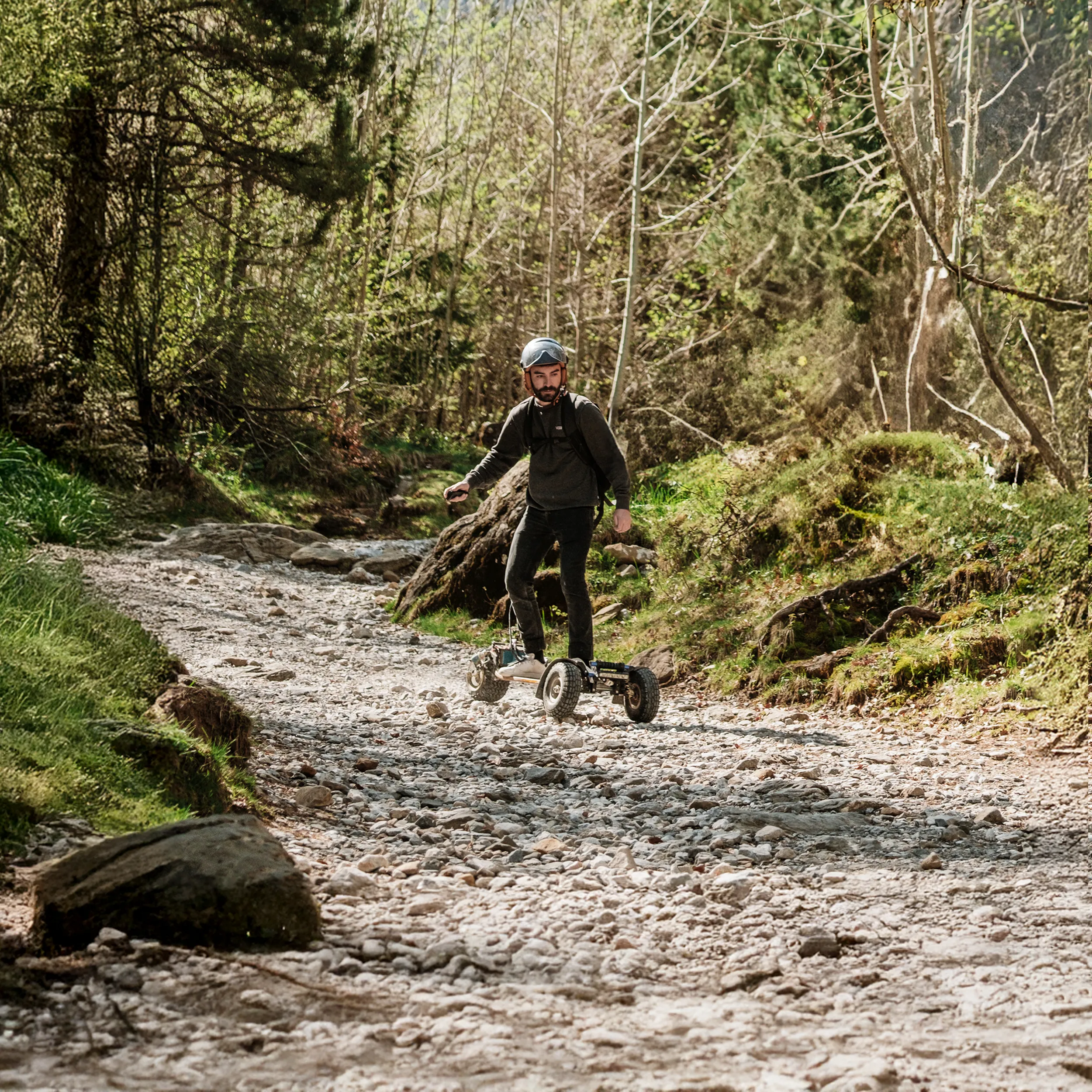Rider con casco sobre Sternboard atravesando el lecho pedregoso de un río en entorno forestal natural